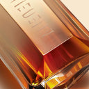Close-up of a gold-colored Mugler Alien Goddess Intense Eau de Parfum 30ml perfume bottle with engraved text on a reflective surface.