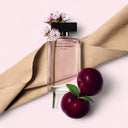 Narciso Rodriguez For Her Musc Noir Eau de Parfum 100ml perfume bottle with flowers and plums on a light pink background