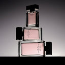 Three stacked Narciso Rodriguez For Her Musc Noir Eau de Parfum 100ml perfume bottles with pink caps and black bodies on a gradient background