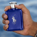 Hand holding a blue Ralph Lauren Polo Blue Eau de Toilette fragrance bottle against a blurred blue background