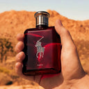 Hand holding a red Ralph Lauren Polo Parfum bottle against a desert background