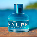 Ralph Lauren Ralph Eau de Toilette 50ml perfume bottle on a wooden surface with a blurred blue background