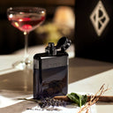 Black and chrome Ralph Lauren Ralph's Club Eau de Parfum 100ml perfume bottle on a table with a blurred glass of red wine in the background