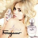 Suki Waterhouse holding a Salvatore Ferragamo Amo Eau de Parfum 100ml bottle with floral background