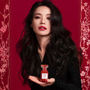 Chinese Actress Shu Qi holding a red Tom Ford Electric Cherry Eau de Parfum 50ml perfume bottle against a red background with floral patterns