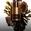 Tom Ford Oud Minérale Eau de Parfum 100ml perfume bottle on a natural background with seaweed and rocks.