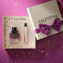 Valentino Donna Born In Roma Eau De Parfum Intense 50ml and a travel sized penspray in a gift box on a purple background