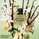 Valentino Donna Born In Roma Green Stravaganza Eau de Parfum 50ml perfume bottle surrounded by vanilla beans and flowers on a light green background