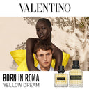 Valentino Uomo Born In Roma Yellow Dream Eau de Toilette perfume bottles with Anwar Hadid and a female models against a natural background