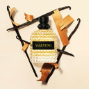 Valentino Uomo Born In Roma Yellow Dream Eau de Toilette 50ml perfume bottle with vanilla beans on a beige background