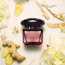 Versace Crystal Noir Eau de Toilette 30ml perfume bottle surrounded by flowers and ginger on a light background
