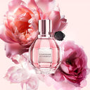 Viktor & Rolf Flowerbomb perfume bottle surrounded by pink flowers on a light pink background