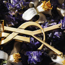 Metalic YSL logo with flowers on a dark background