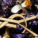 Gold YSL metallic logo with white flowers and purple lavender on a dark background