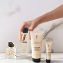 YSL Yves Saint Laurent Libre Fragrance, body balm and other products from the range on a marble surface with a hand holding a bottle.