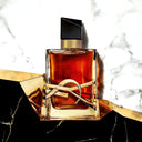 Luxury YSL Yves Saint Laurent Libre Le Parfum perfume bottle with gold cap and base on a marble surface