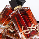 Close up of three YSL Yves Saint Laurent Libre Le Parfum 90ml perfume bottles with gold accents on a white background