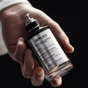 BEAUTE KNOWS Maison Margiela Replica Soul of The Forest perfume bottle held in a hand against a dark background