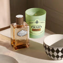 Prada perfume bottle and Prada Infusion De Vanille Candle on a table with a checkered bowl.